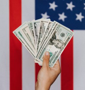 Hand holding cash with American Flag in background