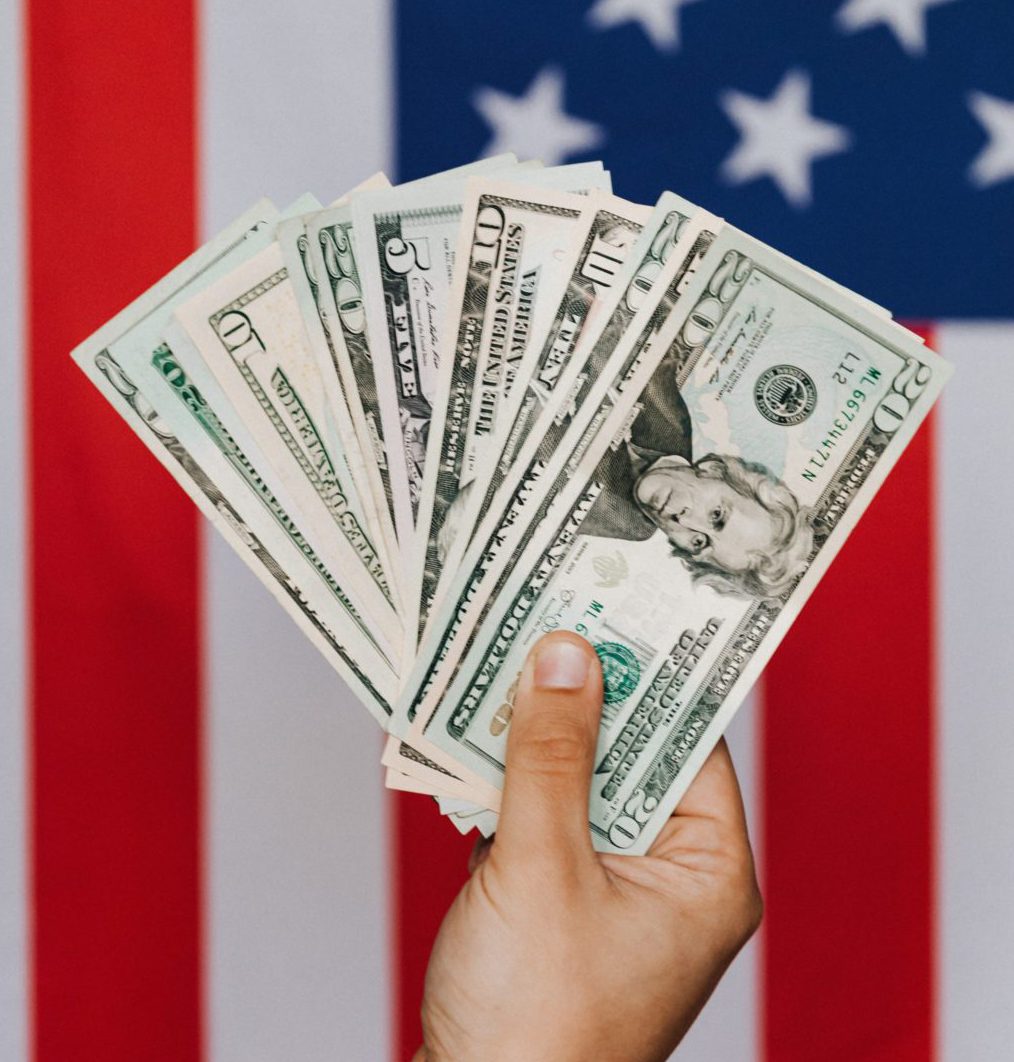 Hand holding cash with American Flag in background
